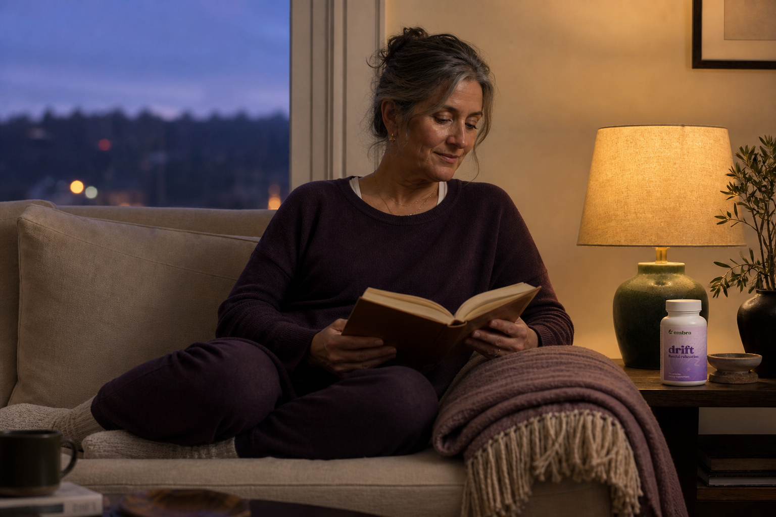 Woman reading beside an Embra drift bottle in a calm evening living room